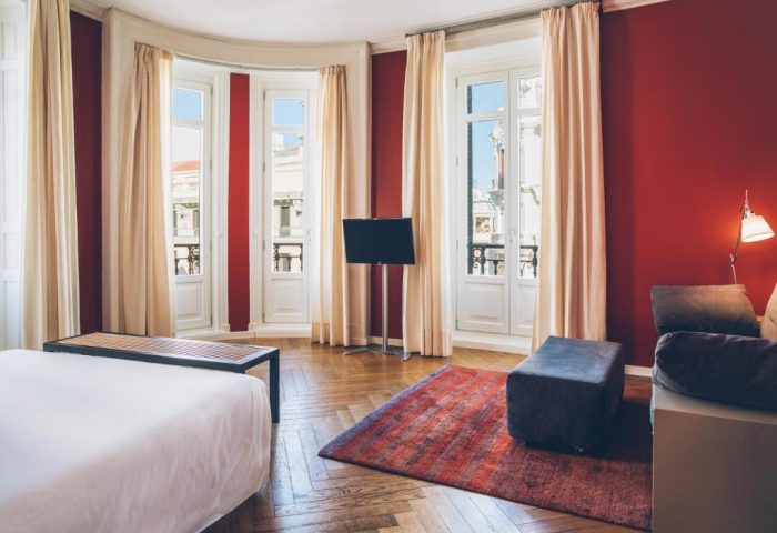 Iberostar Las Letras Gran Via room. Gay-friendly, pet-friendly hotel. Red walls, windows, bed, TV, and hardwood floors. Madrid, Spain.