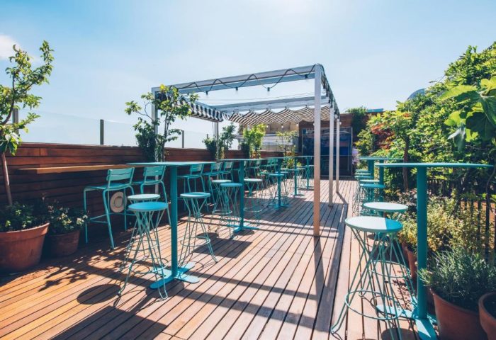Iberostar Las Letras Gran Via's rooftop terrace. Gay-friendly, pet-friendly hotel with turquoise bar stools and tables on a wooden deck.