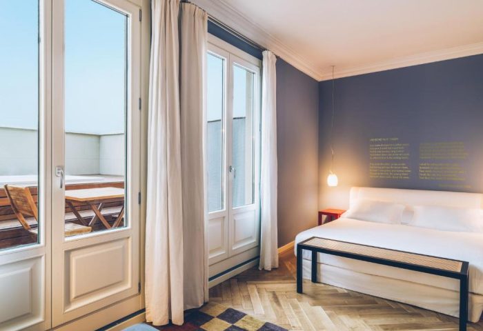 Iberostar Las Letras Gran Vía gay-friendly hotel room. Balcony with table, bed with bench, and hardwood floors. Pet-friendly stay.