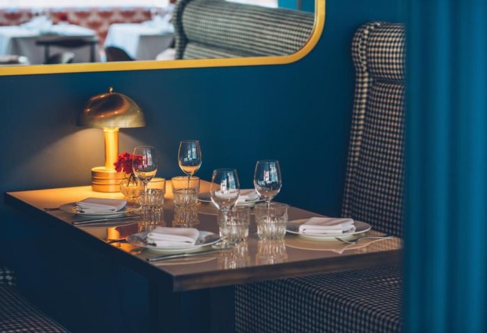 Iberostar Las Letras Gran Vía gay-friendly hotel restaurant. Table setting with wine glasses, plates, and a lamp. Stylish pet-friendly decor.