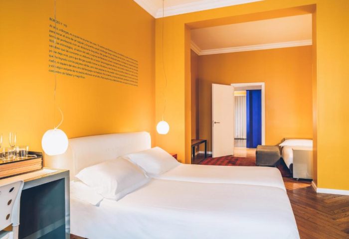 Iberostar Las Letras Gran Via gay-friendly hotel room. Pet-friendly option. Bright yellow walls, double bed, and modern design. Madrid travel.