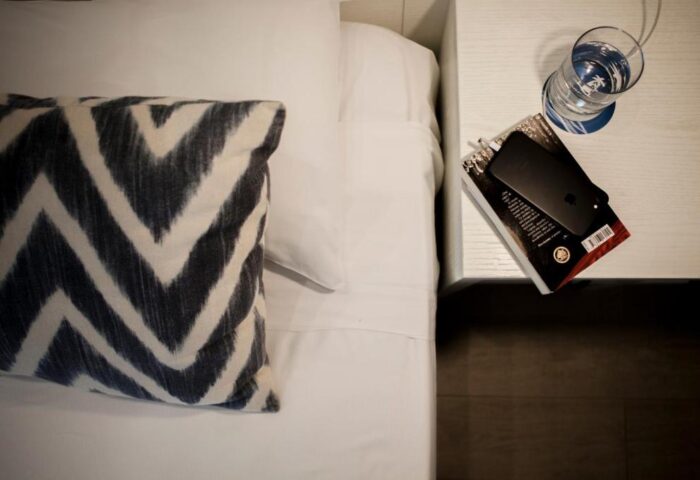 Ibersol Antemare Adults Only gay-friendly hotel room. Bed with patterned pillow, bedside table with book, phone, and glass of water.