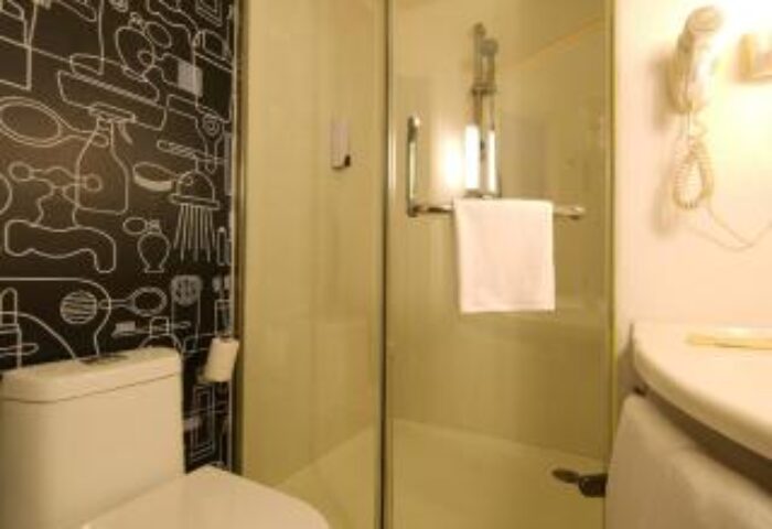 Bathroom at Ibis Beijing Dongdaqiao Hotel. Gay-friendly hotel with shower, toilet, sink, wood floor, and wallpaper. Great for gay travel in Beijing.