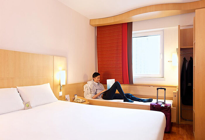 Ibis Beijing Dongdaqiao Hotel: Man using laptop in a room at this gay-friendly hotel. Suitcase nearby, clean design.