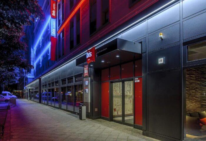 Ibis Berlin Kurfuerstendamm hotel exterior at night. Gay-friendly hotel with red and blue neon lights. Modern facade on Kurfuerstendamm street.