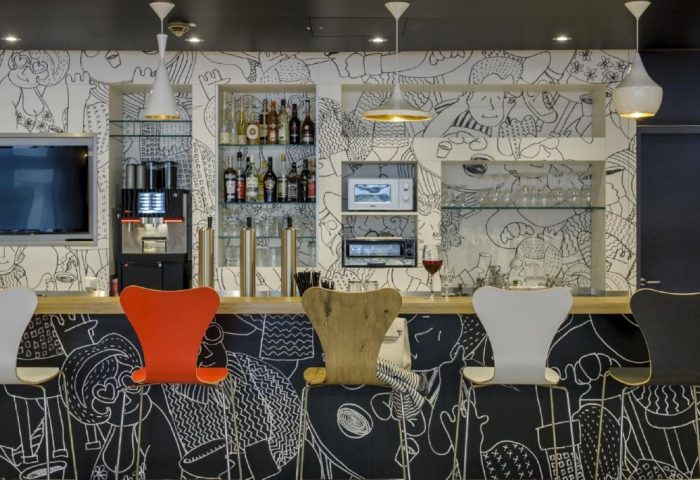 Ibis Berlin Kurfuerstendamm hotel bar. Gay-friendly hotel with quirky, modern design. Bar with stools, drinks, and black & white cartoon mural.