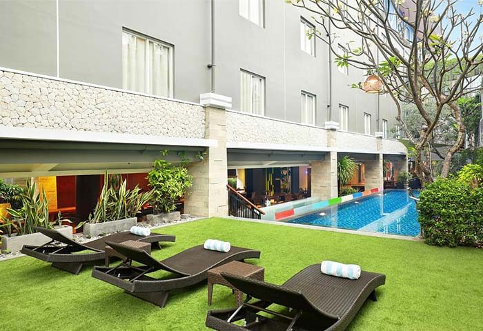 Ibis Budget Bali Seminyak gay-friendly hotel pool view. Lounge chairs on the grass near the pool. Bali gay travel.
