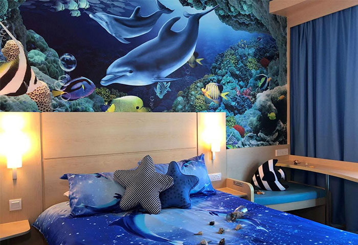 Ibis Hong Kong Central & Sheung Wan Hotel room featuring a vibrant ocean-themed mural, star pillows, & sea shell decor. Gay-friendly hotel.