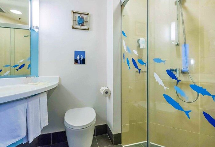 Ibis Hong Kong Central & Sheung Wan Hotel bathroom. Shower with blue fish decals. Gay-friendly hotel room interior.