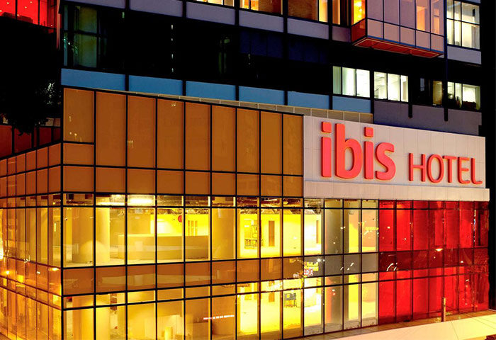 Ibis Hong Kong Central & Sheung Wan Hotel exterior at night. Gay-friendly hotel with modern facade and bright Ibis Hotel sign.
