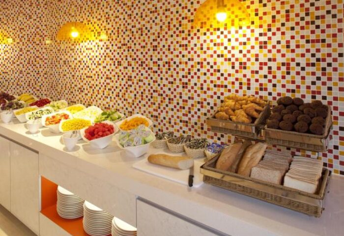 Breakfast buffet at Ibis Hong Kong Central & Sheung Wan Hotel, a gay-friendly hotel. Features fruit, bread, pastries, and colorful mosaic tiles.