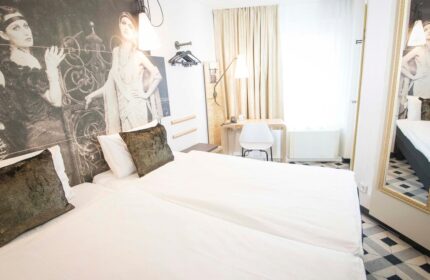 Ibis Hotel Koeln Centrum room. Gay-friendly hotel with twin beds, desk, and vintage-style decor. A comfortable stay in Cologne, Germany.