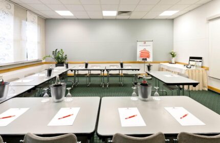 Ibis Hotel Koeln Centrum's conference room setup. Tables, chairs, water bottles, and stationery arranged for a meeting at this gay-friendly hotel.