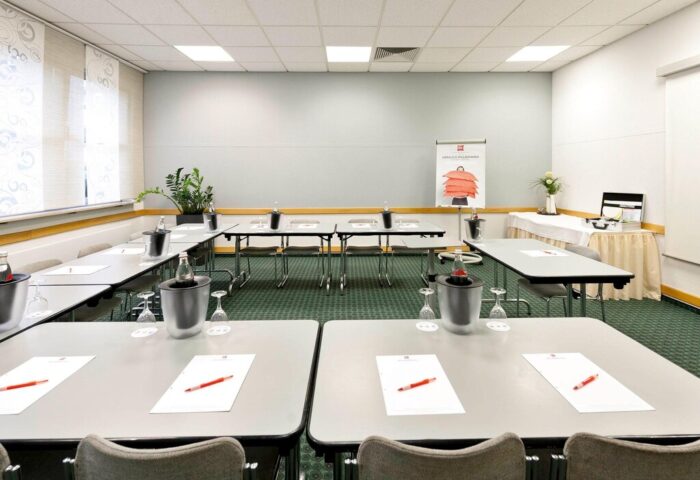 Ibis Hotel Koeln Centrum's conference room setup. Tables, chairs, water bottles, and stationery arranged for a meeting at this gay-friendly hotel.