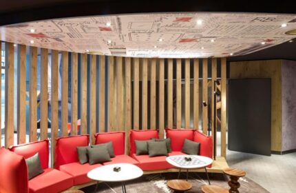 Ibis Hotel Koeln Centrum lounge area. Red sofas, wooden stools, and tables create a modern, gay-friendly space in this Cologne hotel.