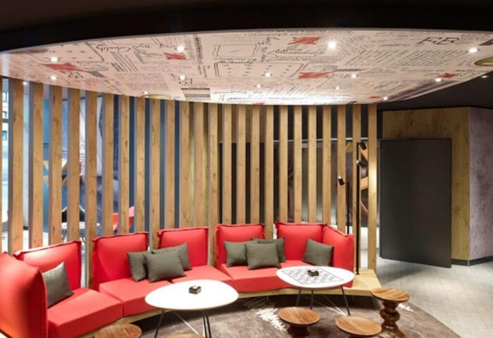 Ibis Hotel Koeln Centrum lounge area. Red sofas, wooden stools, and tables create a modern, gay-friendly space in this Cologne hotel.