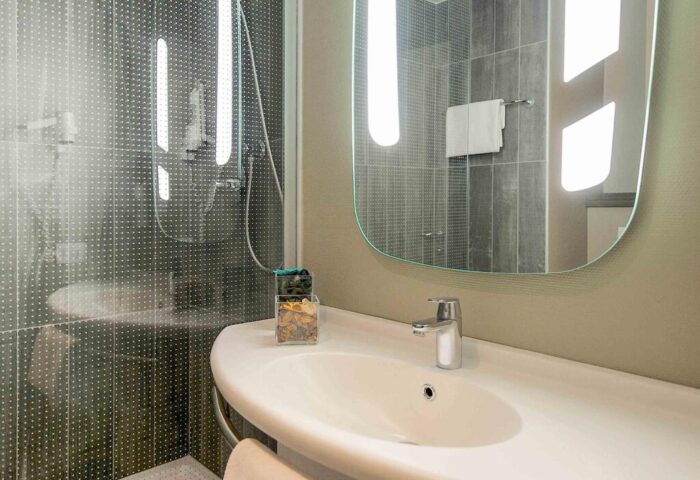 Ibis Milano Centro Hotel bathroom. Modern sink, mirror, and shower in a gay-friendly hotel. Comfortable stay for gay travelers in Milan.
