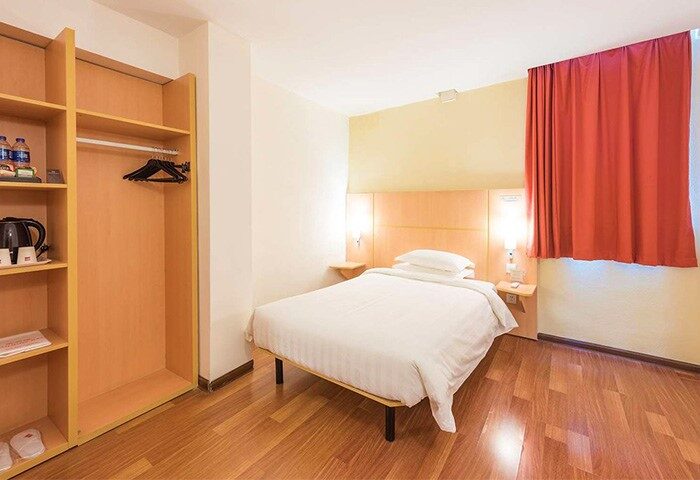 Ibis Shanghai Xujiahui Hotel room. Gay-friendly hotel room with single bed, closet, red curtains, wooden floor. Shanghai travel advice.