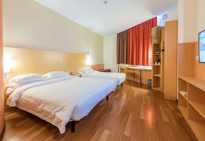 Ibis Shanghai Xujiahui Hotel room. Gay-friendly hotel with twin beds, desk, and TV. Modern decor, wooden floor. Comfortable stay in Shanghai.