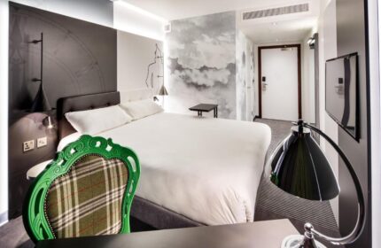 Ibis Styles London Southwark Hotel room. Gay-friendly hotel with double bed, stylish decor, green chair, and modern amenities. Ideal for gay travel.