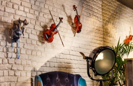 Ibis Styles London Southwark Hotel decor: violins, a mask, and a stage light adorn a brick wall. Gay-friendly hotel interior design.