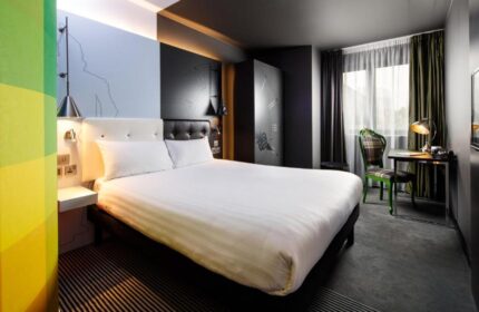 Ibis Styles London Southwark Hotel room. Gay-friendly hotel with a double bed, desk, chair, and TV. Modern design and colorful accents.