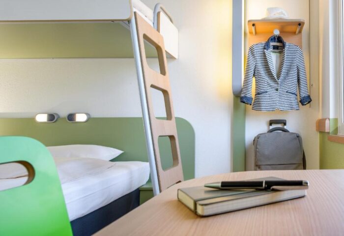Ibis budget Berlin Kurfurstendamm gay-friendly hotel room. Bunk bed, desk with notebook & pen, jacket, & suitcase. Berlin travel for gay men.