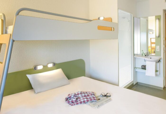 Ibis budget Berlin Kurfurstendamm room. Bunk bed, bathroom, shirt, glasses, newspaper. Gay-friendly hotel for gay men traveling in Berlin.