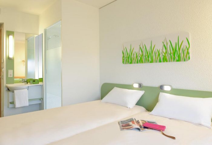 Ibis budget Berlin Kurfurstendamm gay-friendly hotel room. Twin beds, magazine, and pink wallet. Modern, clean design for gay travelers.