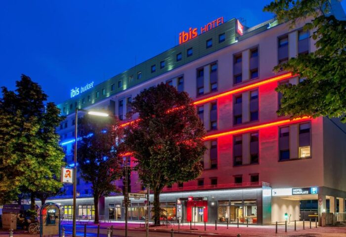 Ibis budget Berlin Kurfurstendamm, a gay-friendly hotel. Building illuminated with red and blue lights at night. Hotel in Berlin.