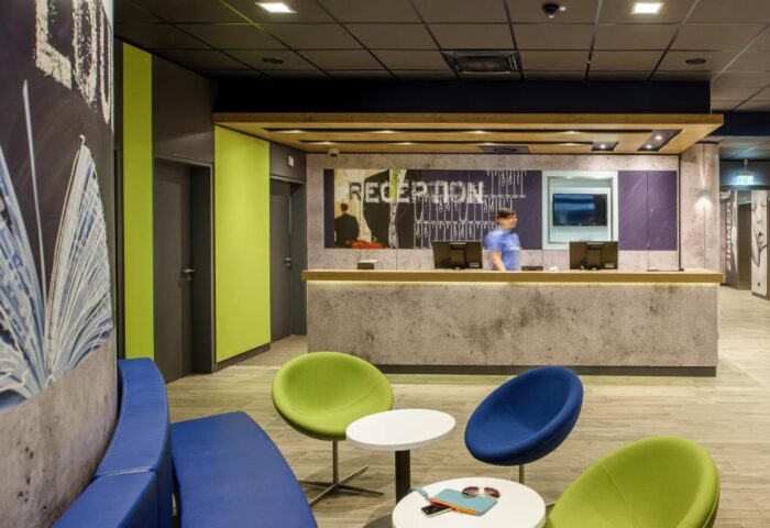 Ibis budget Berlin Kurfurstendamm lobby. Gay-friendly hotel reception area with colorful seating. Modern design, welcoming atmosphere.