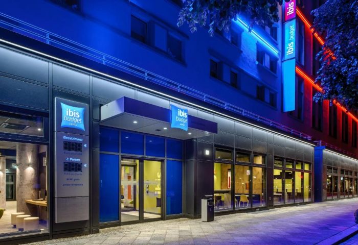 Ibis budget Berlin Kurfurstendamm, a gay-friendly hotel. Facade with neon lights. Modern design, perfect for gay travelers in Berlin.