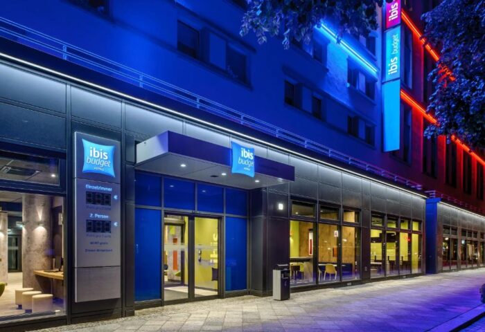 Ibis budget Berlin Kurfurstendamm, a gay-friendly hotel. Facade with neon lights. Modern design, perfect for gay travelers in Berlin.