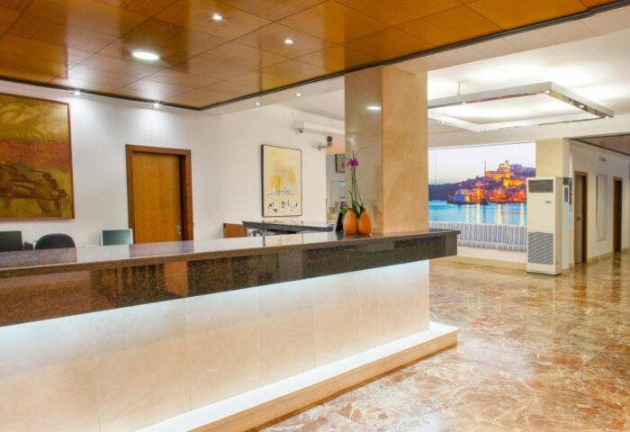 Lobby of gay-friendly hotel in Ibiza Playa. Reception desk, marble floor, and artwork. A welcoming space for gay travelers in Ibiza.