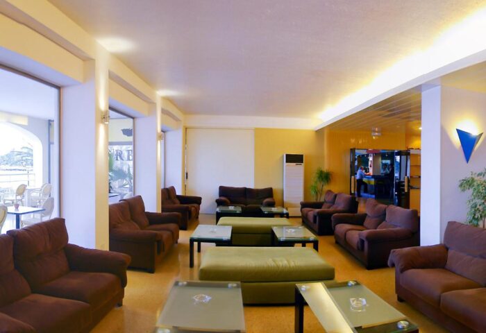 Ibiza Playa gay-friendly hotel lounge area. Brown sofas, glass tables, and a relaxed vibe. Perfect for gay travelers seeking comfort.