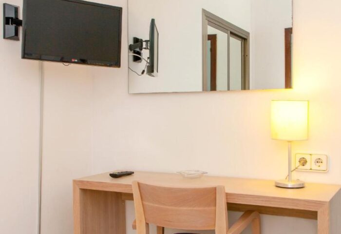 Gay-friendly hotel Ibiza Playa room featuring a desk, chair, lamp, mirror, and TV. Ideal for gay men traveling to Ibiza, Spain.