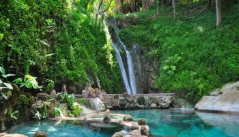 Imanta Resorts Punta De Mita gay-friendly hotel view. Waterfall flowing into a clear pool, lush greenery. Perfect for gay men's travel.