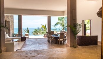 Imanta Resorts Punta De Mita gay-friendly hotel view. Ocean view villa interior with dining table, lounge, and outdoor pool. Luxury travel.