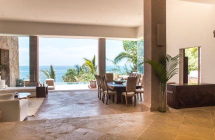 Imanta Resorts Punta De Mita gay-friendly hotel view. Ocean view villa interior with dining table, lounge, and outdoor pool. Luxury travel.