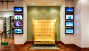 Imperial Palace Boutique Hotel's unique lobby area. Yellow high-back chair and wall-mounted TVs. Gay-friendly hotel interior design.
