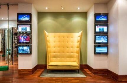Imperial Palace Boutique Hotel's unique lobby area. Yellow high-back chair and wall-mounted TVs. Gay-friendly hotel interior design.