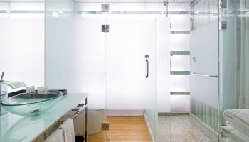 Imperial Palace Boutique Hotel bathroom. Glass countertop with a glass bowl sink. Walk-in shower with glass doors. Gay-friendly hotel.