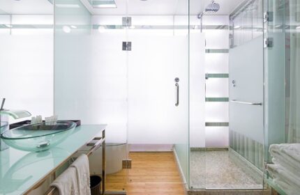 Imperial Palace Boutique Hotel bathroom. Glass countertop with a glass bowl sink. Walk-in shower with glass doors. Gay-friendly hotel.