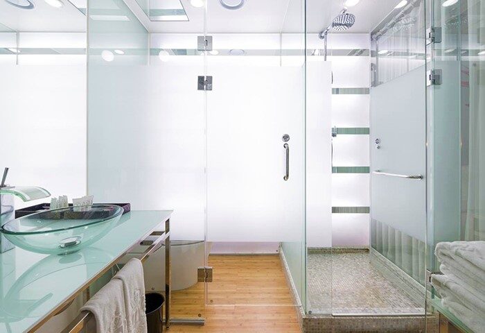 Imperial Palace Boutique Hotel bathroom. Glass countertop with a glass bowl sink. Walk-in shower with glass doors. Gay-friendly hotel.