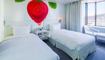 Imperial Palace Boutique Hotel room with twin beds, strawberry wall art, and city view. A gay-friendly hotel for gay men travelers.