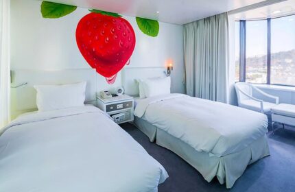 Imperial Palace Boutique Hotel room with twin beds, strawberry wall art, and city view. A gay-friendly hotel for gay men travelers.