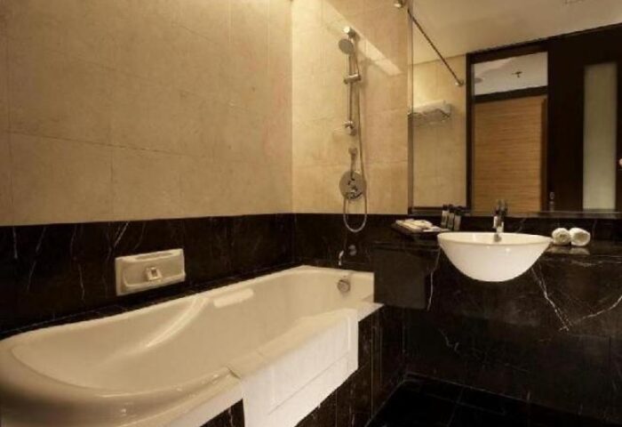 Impiana KLCC Hotel bathroom. Bathtub, sink, and shower in a marble-accented, gay-friendly hotel room. Modern design for LGBTQ+ travelers.
