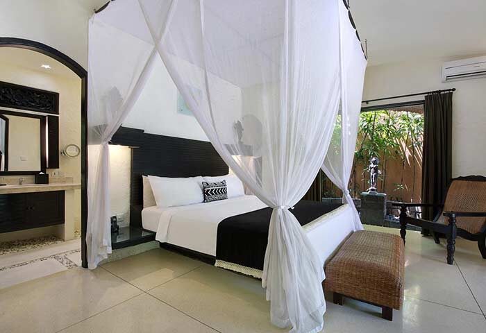 Impiana Private Villas Seminyak bedroom. Gay-friendly hotel with canopy bed, ensuite bathroom, and outdoor garden view. Luxury Seminyak villa.