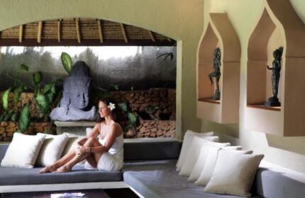 Impiana Private Villas Seminyak: Woman relaxing in a luxury villa. Gay-friendly hotel with Balinese decor, Buddha statue, and serene ambiance.