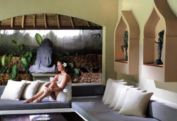 Impiana Private Villas Seminyak: Woman relaxing in a luxury villa. Gay-friendly hotel with Balinese decor, Buddha statue, and serene ambiance.